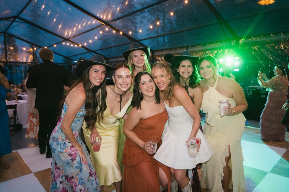 Bride and bridesmaids in cowboy hats posing together under green light