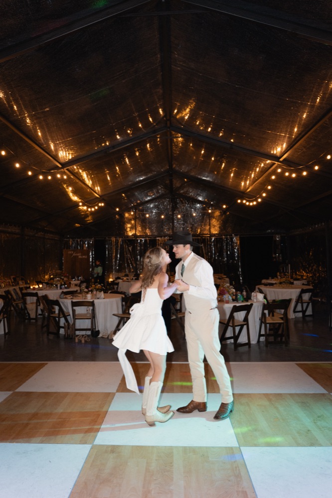 Couple dancing alone on a checkered dance floor under string lights at night