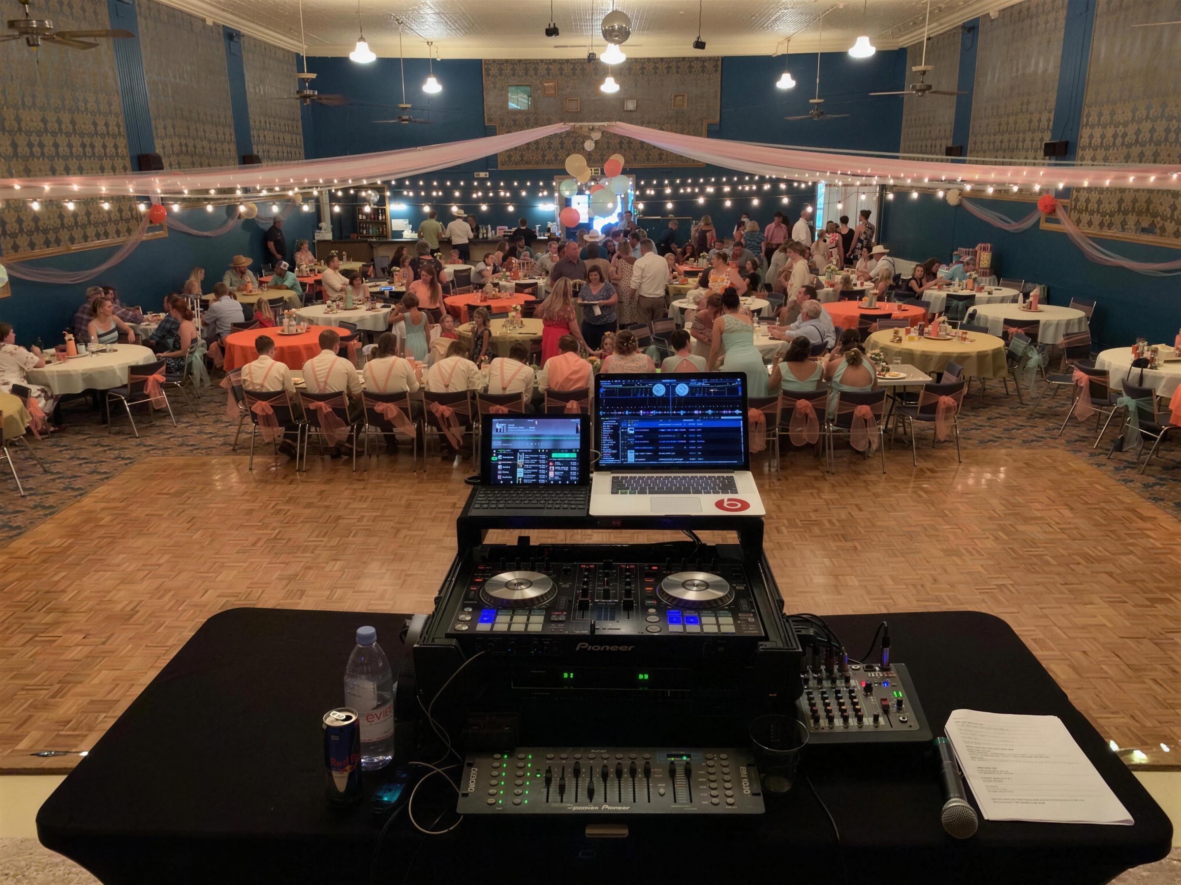 DJ table facing a ballroom of set reception tables