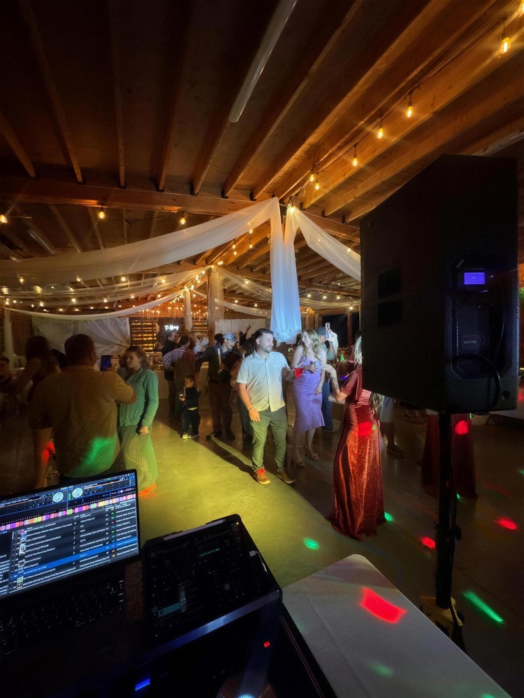 Lit-up dance floor under string lights and white draping, guests dancing