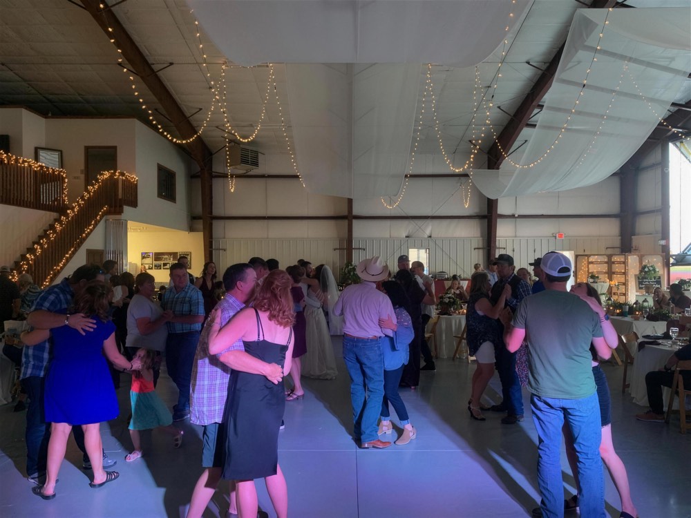 Couples dancing in a hall under string lights