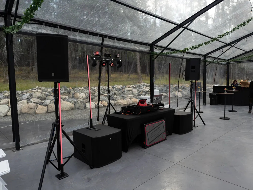 Angled view of the DJ booth, speakers and LED light pillars before a reception
