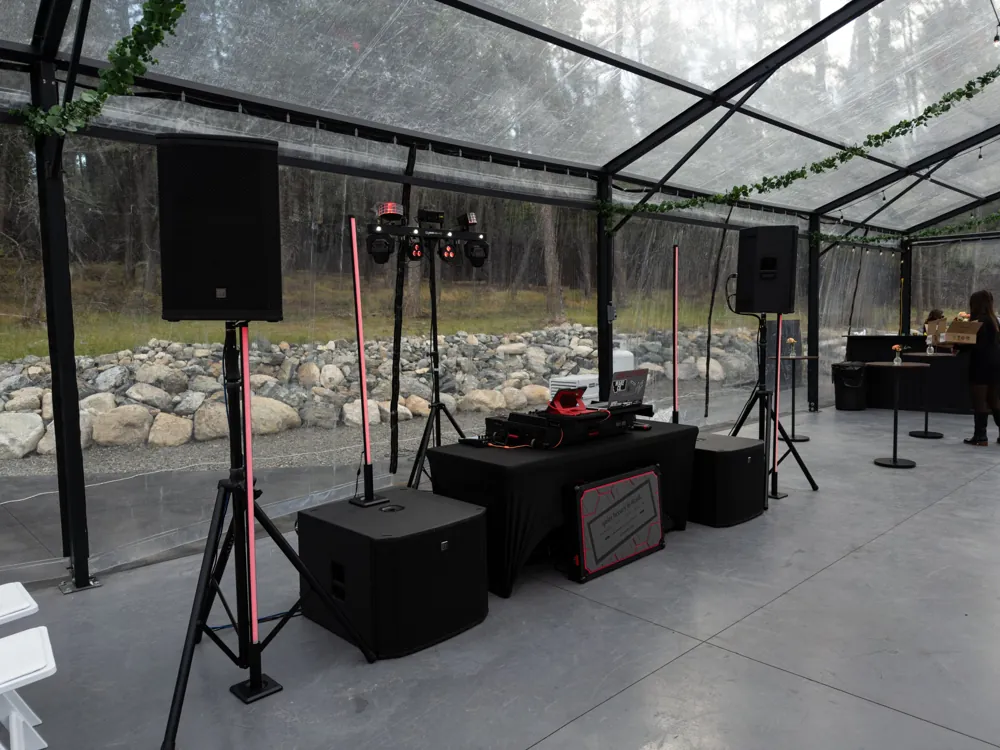 Angled view of the DJ booth, speakers and LED light pillars before a reception