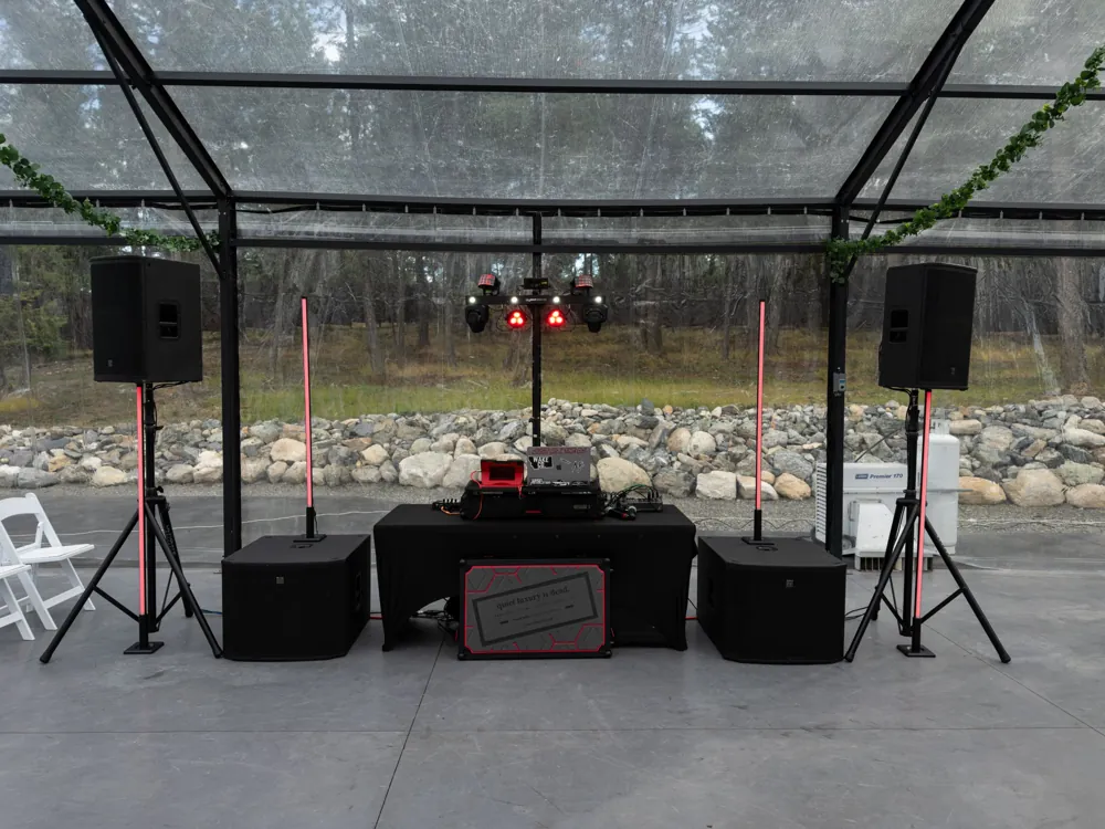 Full DJ rig with two speakers, two subwoofers, LED pillars and an effects light bar in a clear tent
