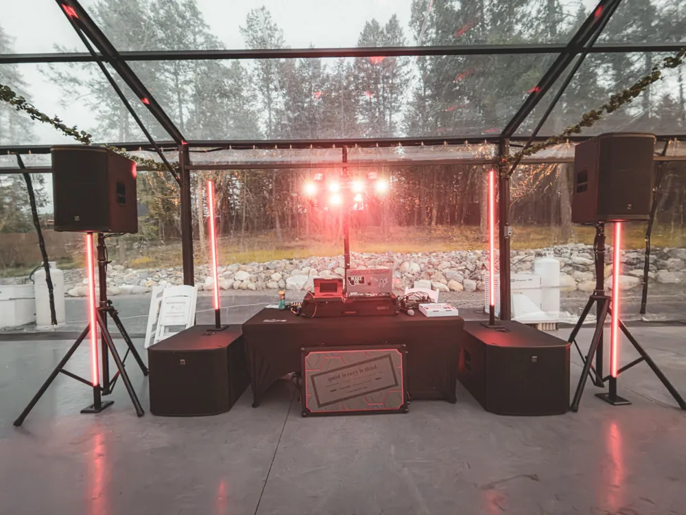 Coach Mike Entertainment DJ setup with red LED light pillars and moving-head lights inside a clear reception tent